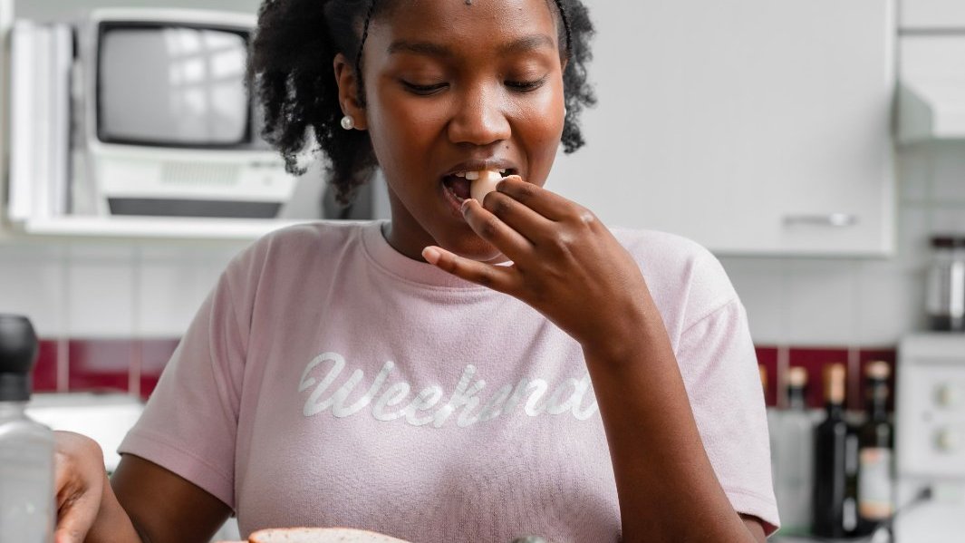 A Black woman reflecting on her emotions with food nearby.