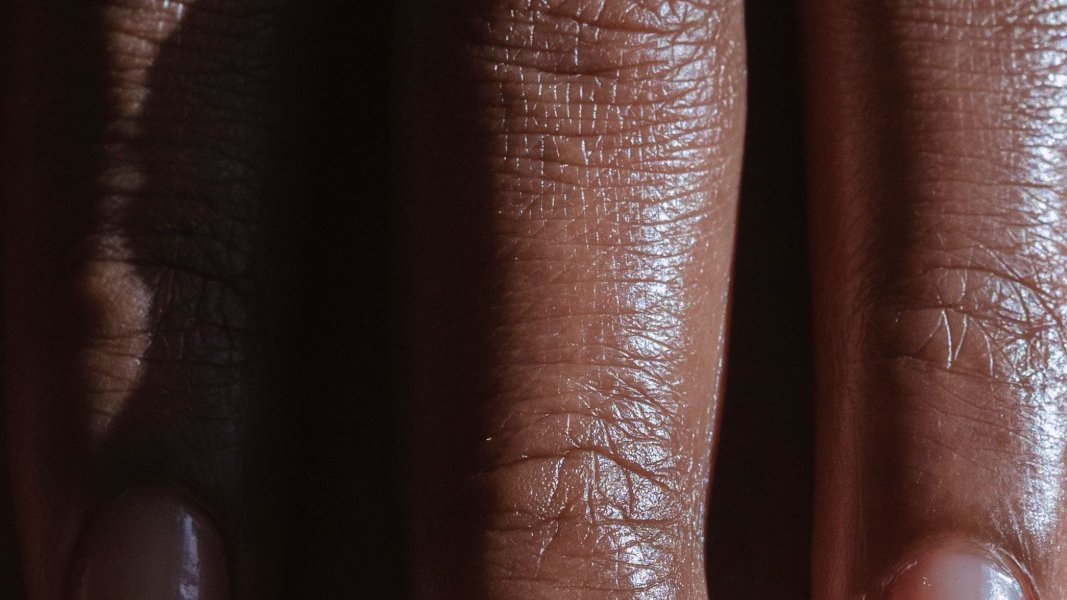 A Black girl sitting at a desk, picking at her skin while studying.