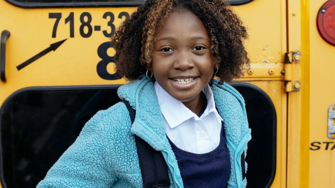 A young Black girl studying with books and a laptop.