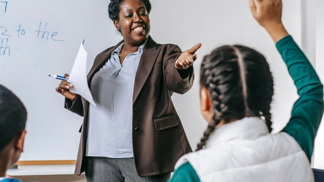 A teacher working with a student in a classroom setting.