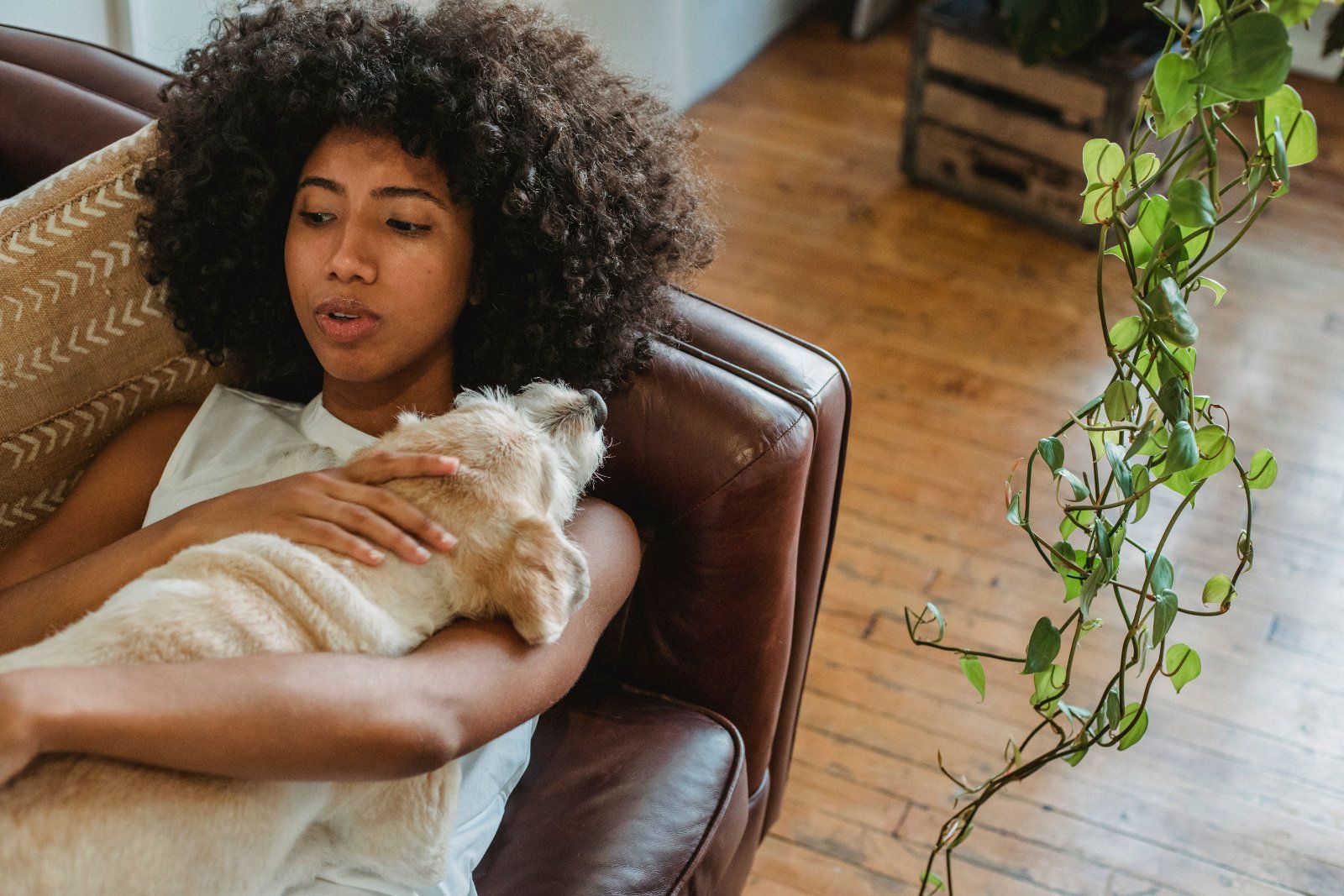 Black woman writing in a journal while sitting at home beside a laptop.