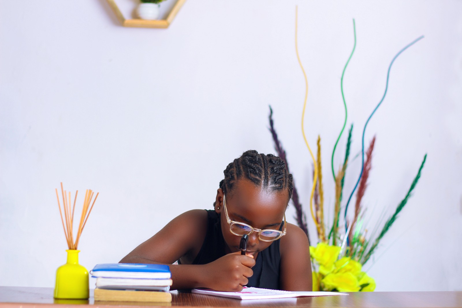 A young Black girl reading a book with a thoughtful expression.