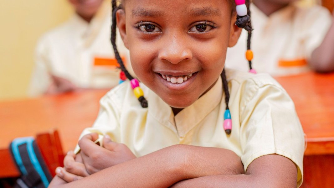 A Black girl looking thoughtful in a classroom.