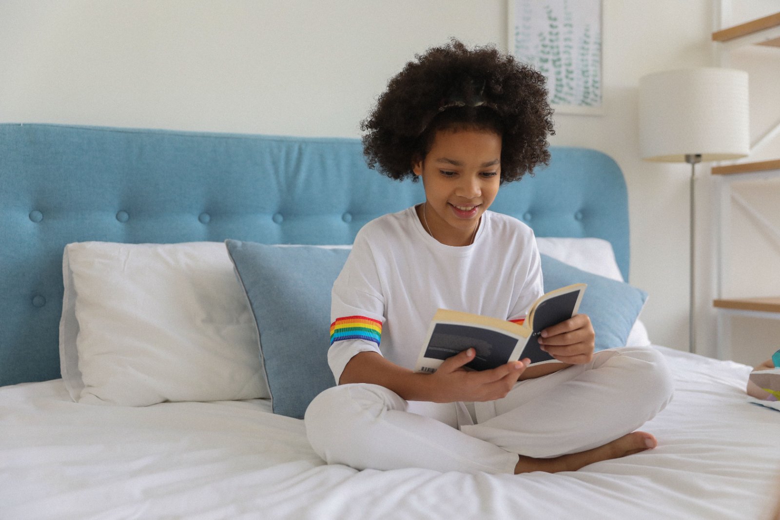Black mother and daughter sitting closely together and looking through a book while having a warm conversation.