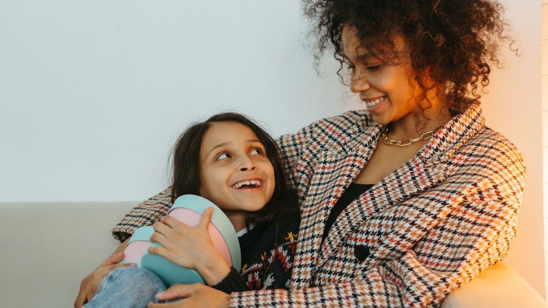 Black mother comforting her daughter during a quiet moment at home.